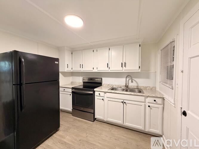A kitchen with black appliances and white cabinets.