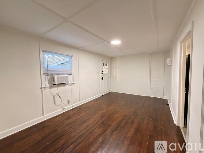 A room with wooden flooring and white walls.