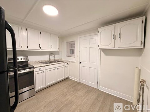 A kitchen with white cabinets and a black refrigerator.