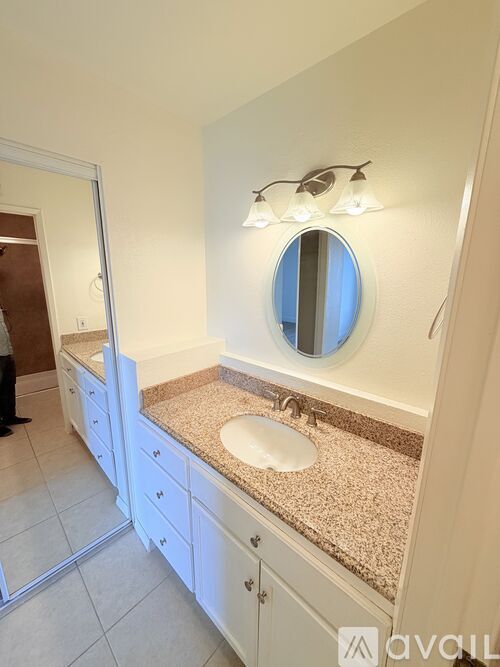 A bathroom with a sink, mirror, and lighting fixture.
