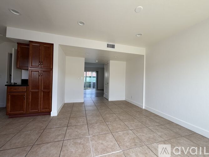 A spacious room with tiled flooring and a cabinet in the corner.
