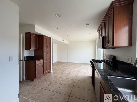 A kitchen with brown cabinets and a black countertop.