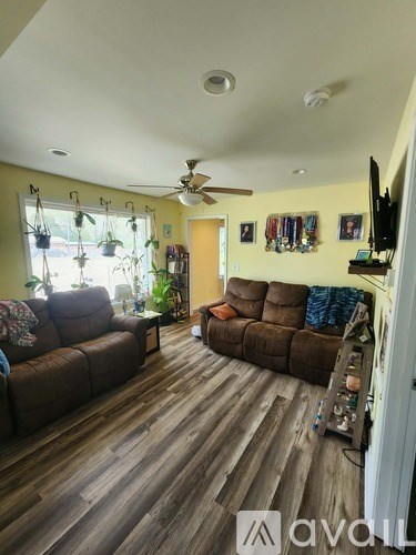 A living room with a brown sofa and a ceiling fan.