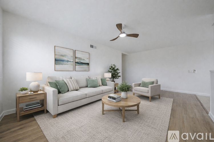 A living room with a white couch, a coffee table, and a ceiling fan.