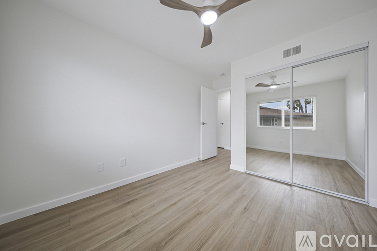 A spacious room with a ceiling fan and a view of a window through a glass door.
