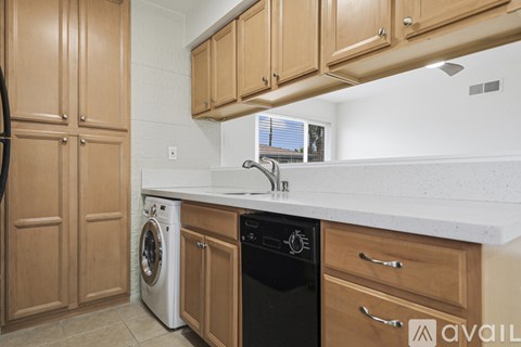 A kitchen with wooden cabinets and a black dishwasher.