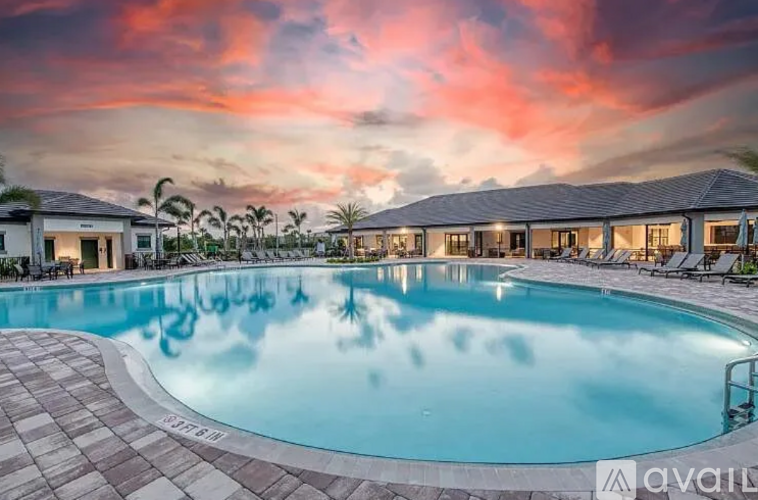 A large swimming pool surrounded by a tiled patio and lounge chairs.