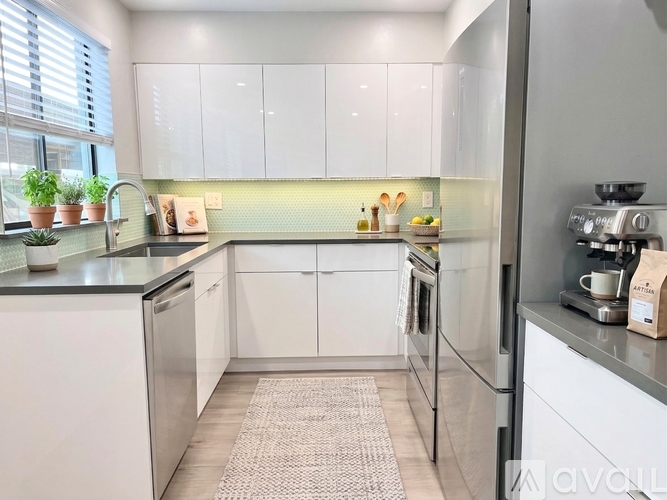 A kitchen with white cabinets and a grey counter top.