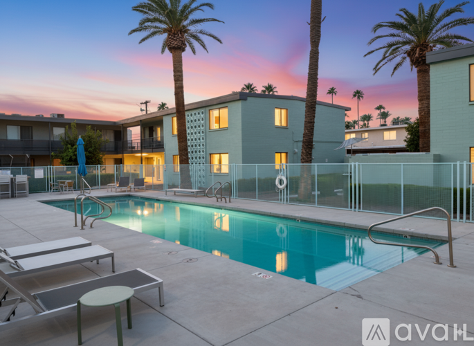 A pool surrounded by palm trees and a building with a balcony.