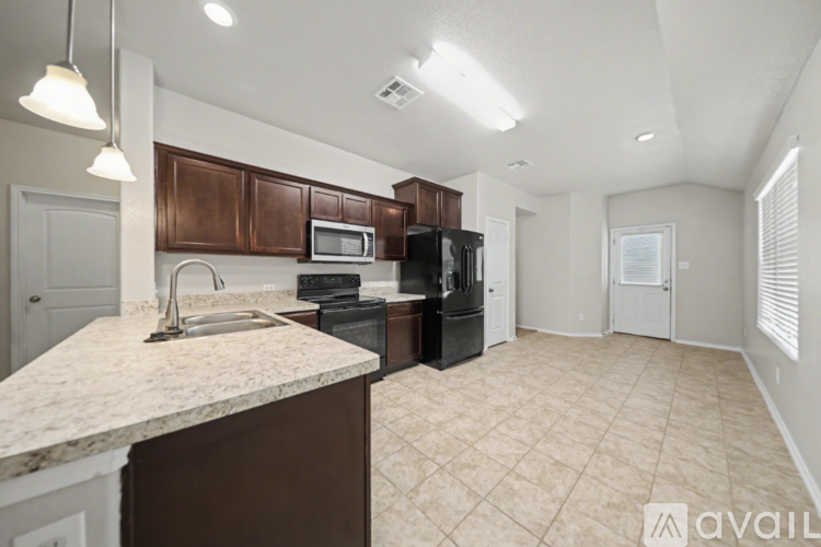 A kitchen with brown cabinets and a marble countertop.