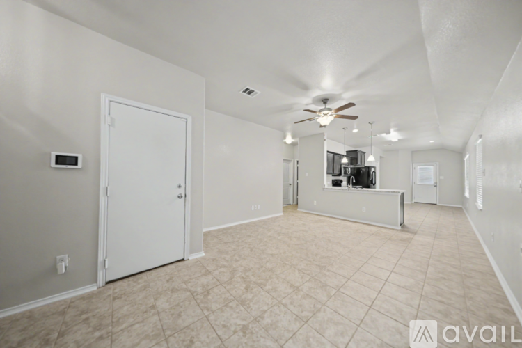 A spacious room with a ceiling fan and a door leading to another room.