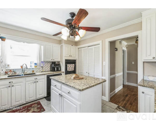 A kitchen with white cabinets and a granite countertop.