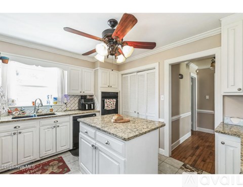 A kitchen with white cabinets and a granite countertop.