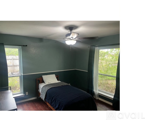 A bedroom with a bed, a window, and a ceiling fan.