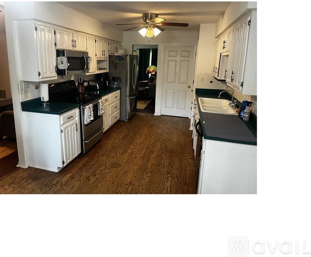 A kitchen with white cabinets and black countertops.
