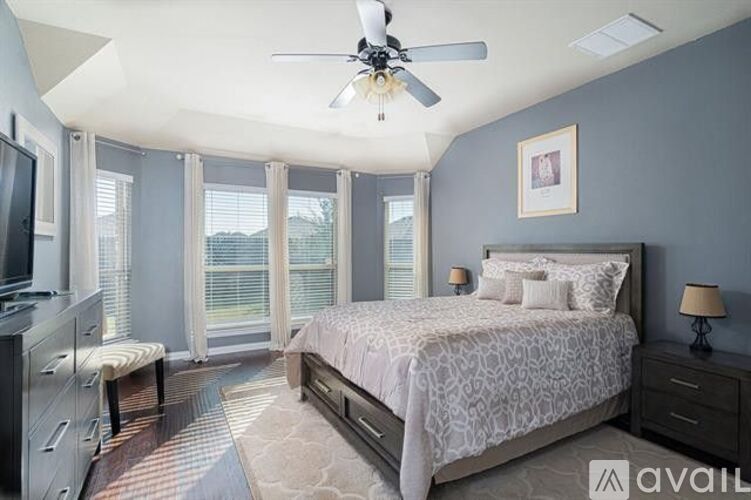 A bedroom with a bed, a ceiling fan, and a window with blinds.