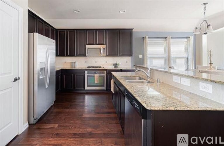 A kitchen with dark wood cabinets and a granite countertop.