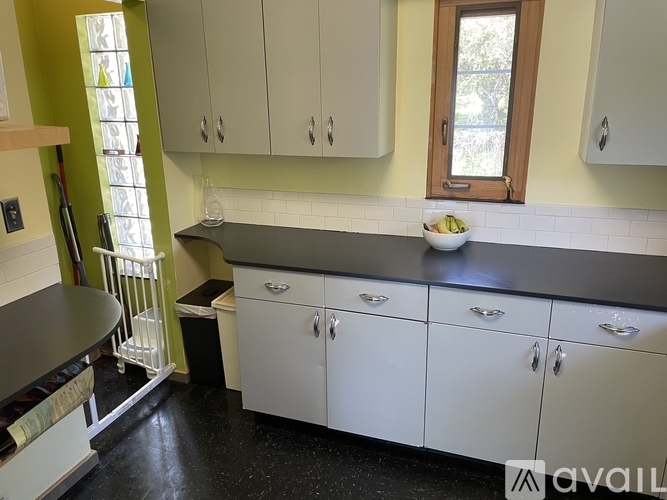 A kitchen with white cabinets and a black countertop.