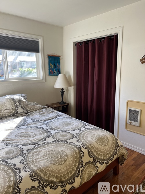 A bedroom with a bed, nightstand, and window.
