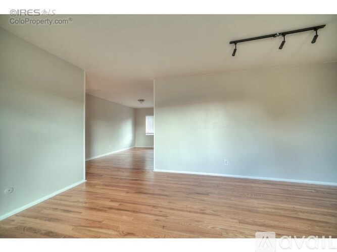 A room with wooden flooring and white walls is available for rent.