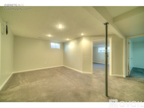 A spacious room with carpeted floor and white walls.
