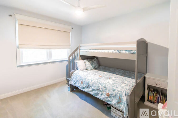 A bedroom with a bunk bed and a window with blinds.