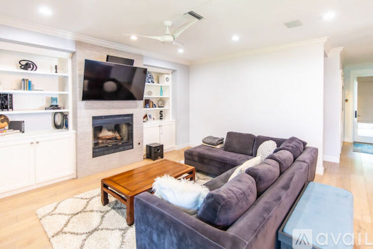 A living room with a grey couch, a fireplace, and a television mounted on the wall.