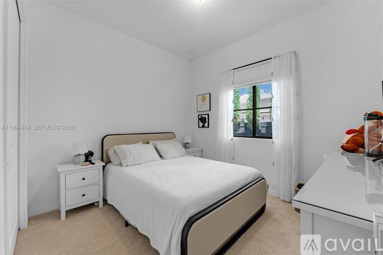 A bedroom with a large bed, nightstand, and window.