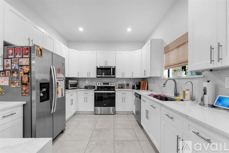 A modern kitchen with white cabinets and appliances.