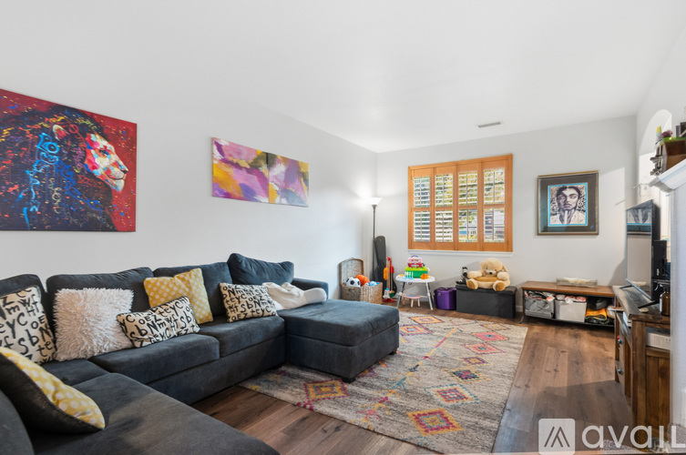 A living room with a grey couch and a painting on the wall.