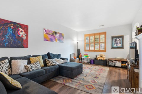 A living room with a grey couch and a painting on the wall.