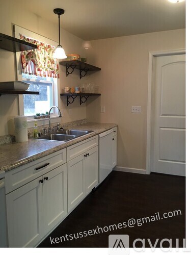 A kitchen with white cabinets and a granite countertop.