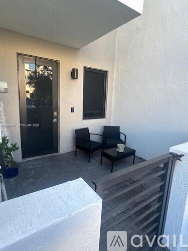 A patio with a black chair and a small table.
