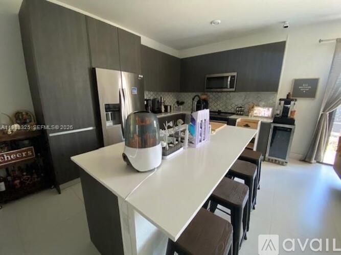 A modern kitchen with a white island and stainless steel appliances.