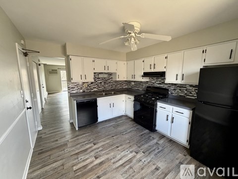 A kitchen with black appliances and white cabinets.