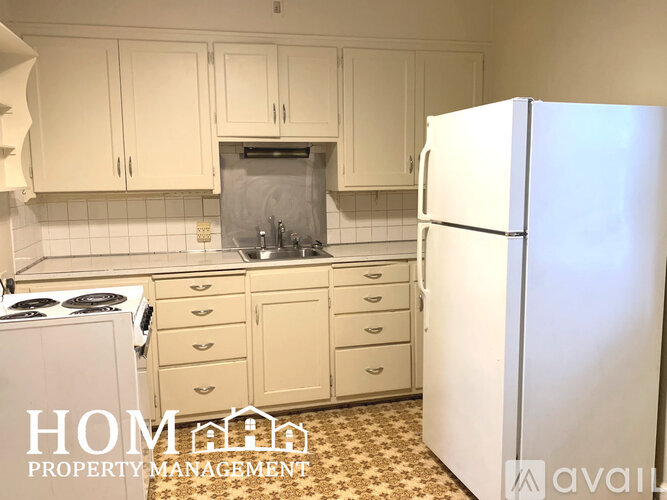 A kitchen with white cabinets and a white refrigerator.