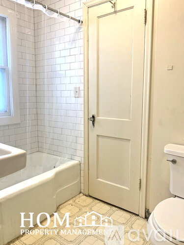 A white door is closed in a bathroom with a white toilet and a white bathtub.