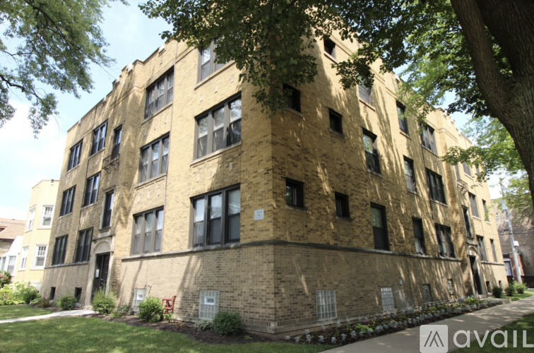 A tall building with many windows is surrounded by trees.