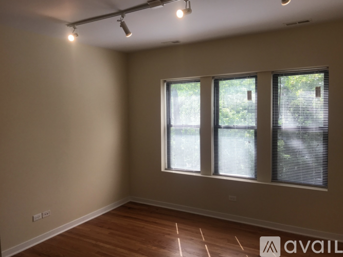 A room with wooden flooring and three windows.
