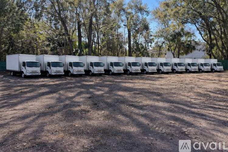 A row of white trucks are parked in a lot.