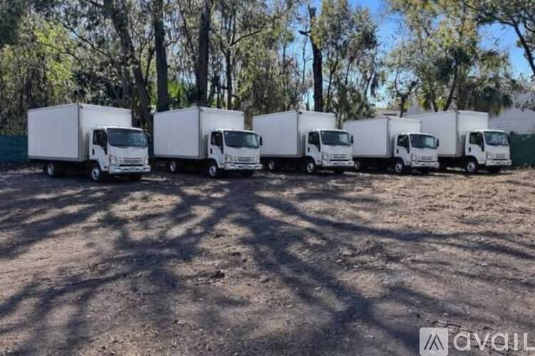 A row of white trucks are parked in a lot.
