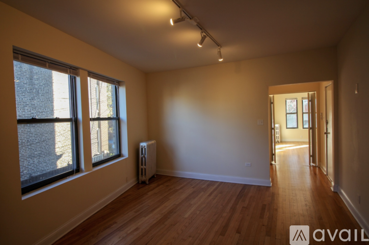 A room with wooden floors and a window with a view of a brick building outside.
