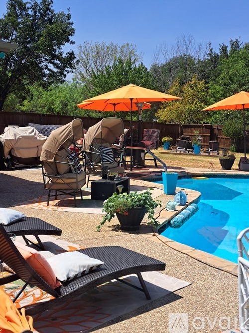 A poolside patio with chairs and umbrellas.