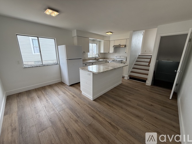 A kitchen with wooden floors and white appliances.