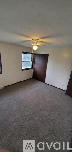 A room with a carpeted floor and a ceiling fan.
