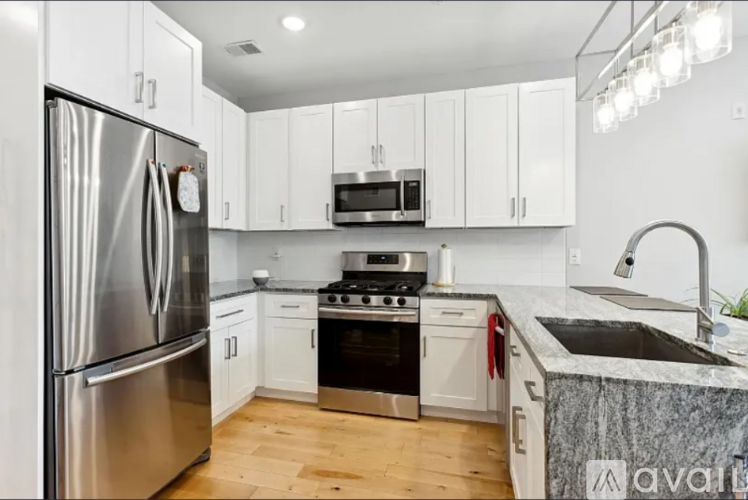A kitchen with a stainless steel refrigerator and white cabinets.