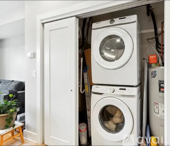 A white door is open to reveal a stack of white washing machines.