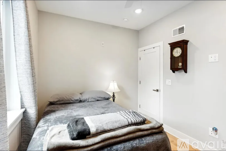 A bedroom with a bed, a clock, and a window.