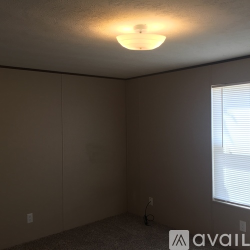 A room with a carpeted floor and a window with blinds.
