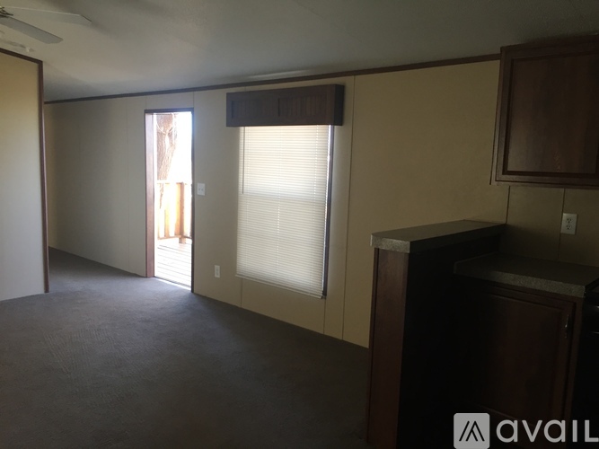 A room with a brown cabinet and a window with blinds.